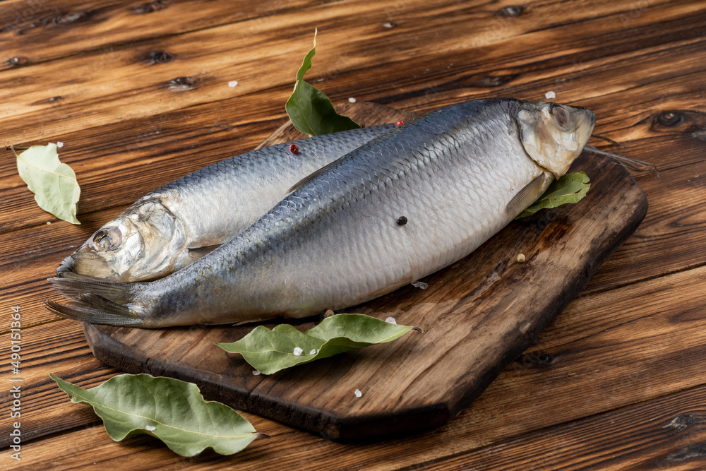 two salted herring on a wooden table with spices two salted herring on a wooden table with spices