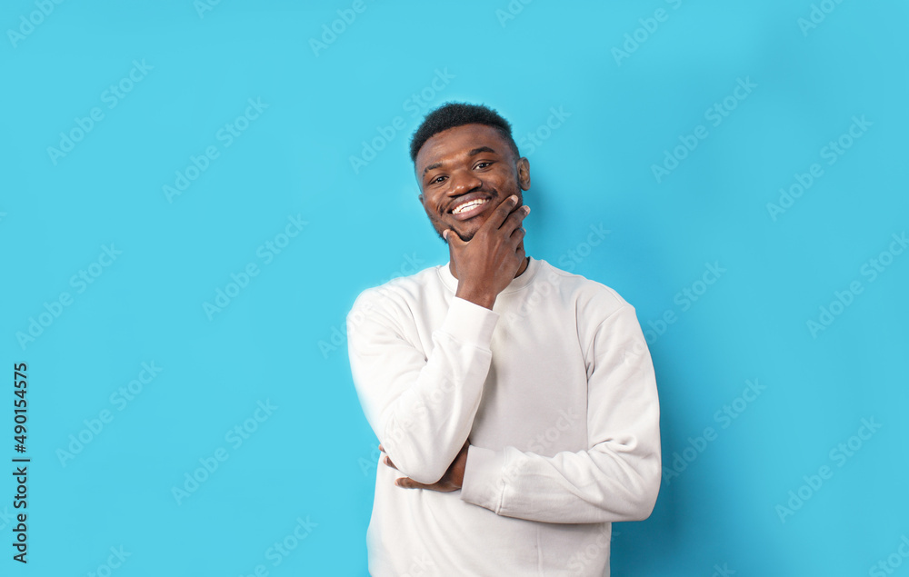 A young African-American man in a white T-shirt laughs on a blue isolated background A young African-American man in a white T-shirt laughs on a blue isolated background