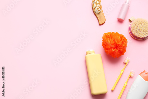 Bottles of cosmetic products and bath accessories on pink background