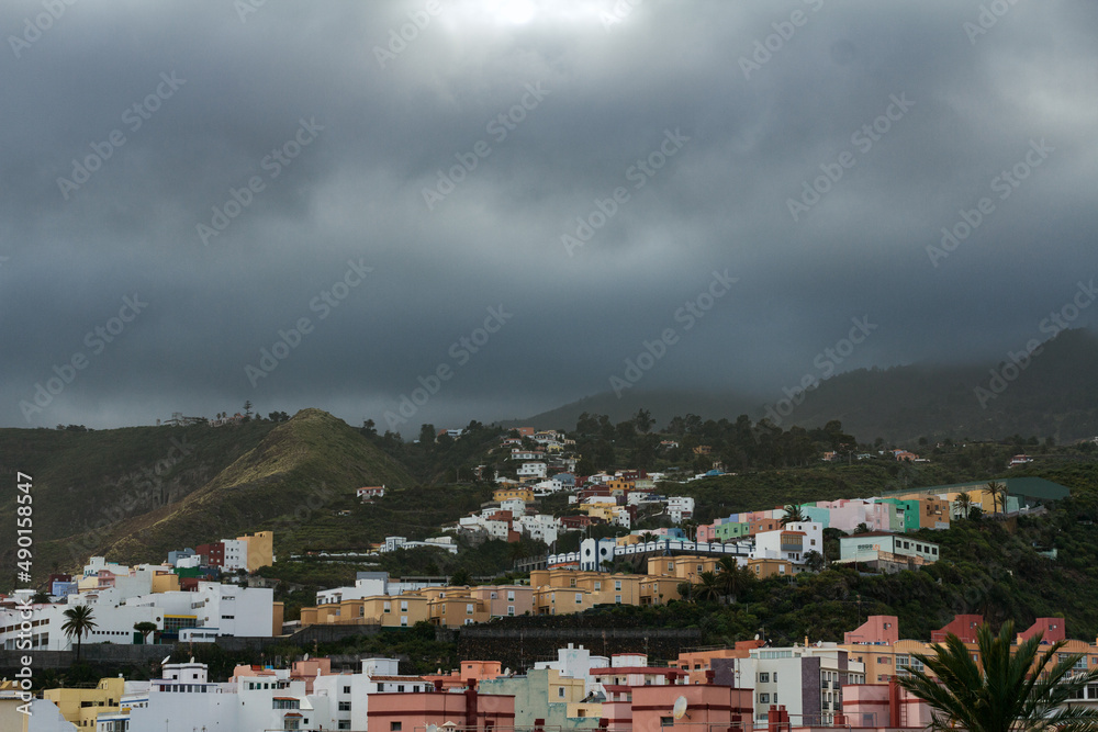 Scenic view on volcanic mountain valley and typical house facades of village town in La Palma (Canary Islands, Spain). Moody, cloudy and foggy panoramic countryside landscape.
