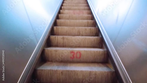 A young man get off the moving up escalator or moving staircase to the exit