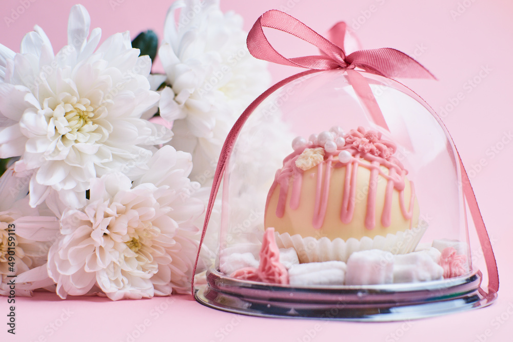 Chocolate candy in a gift box on a pink background with flowers Chocolate candy in a gift box on a pink background with flowers