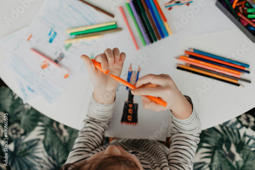 The boy draws with felt-tip pens
