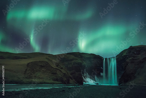 Fotografia aurora borealis over skogafoss waterfall in iceland