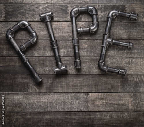 Cast iron pipes and fittings in a shape of word pipe on a rustic wooden table