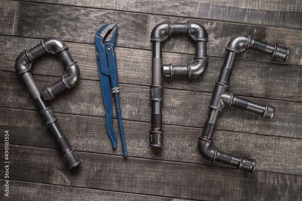 Cast iron pipes and fittings in a shape of word pipe on a rustic wooden