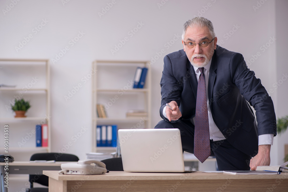 Old male employee sitting at workplace Old male employee sitting at workplace