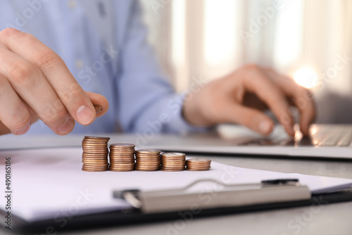 Man stacking coins at table indoors, closeup