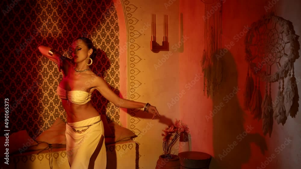 sexy lady with big breasts and sexy body is dancing belly dance in oriental interior of palace
