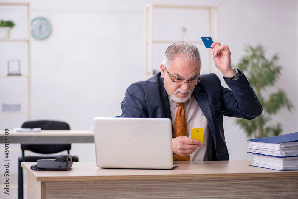 Old male employee holding credit card in the office