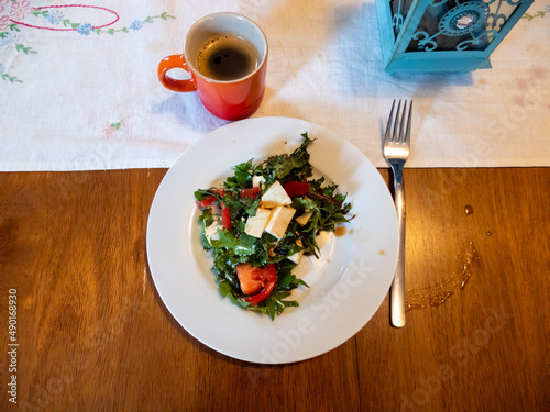 fresh salad with cheese and tomato served with fresh espresso in a cute orange mug