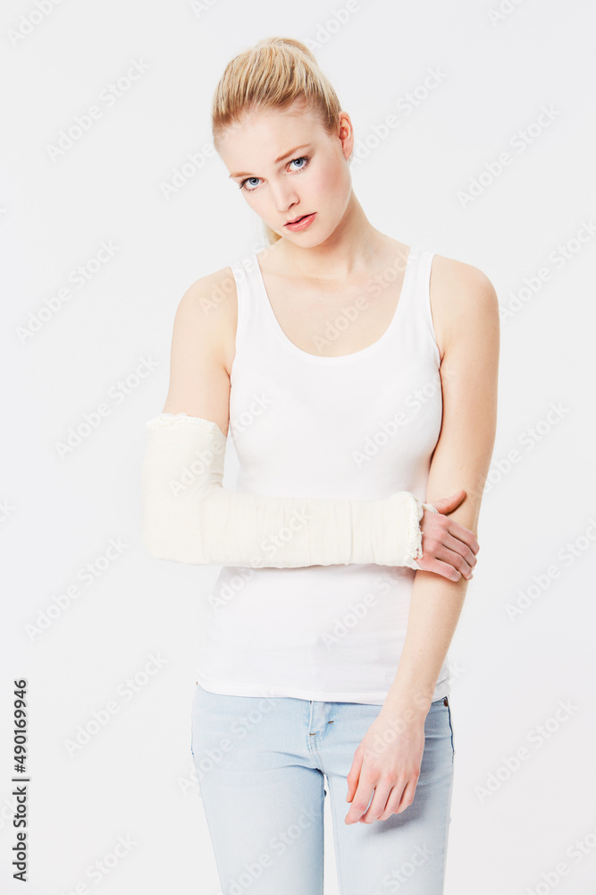Feeling the affects of a bad injury. Portrait of an unhappy girl with a bandaged arm. Feeling the affects of a bad injury. Portrait of an unhappy girl with a bandaged arm.