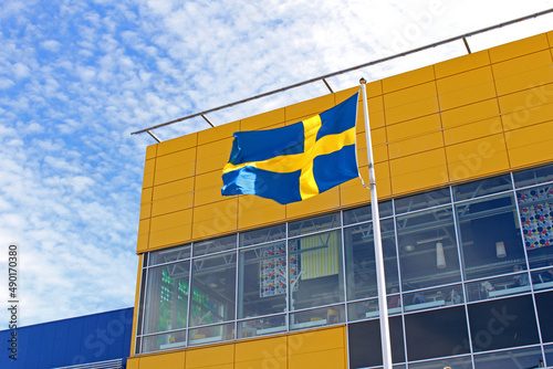 Canvas Print Low angle shot of the Ikea building with the flag of Sweden in front of it