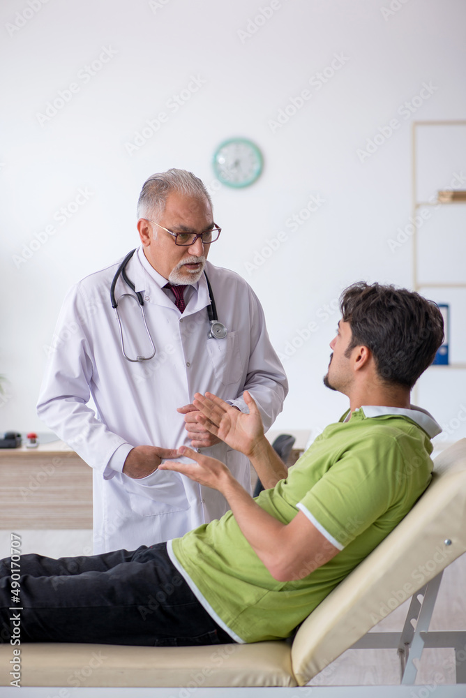 Obraz premium Young male patient visiting old male doctor