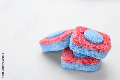 Dishwasher detergent tablets on light background, closeup. Space for text