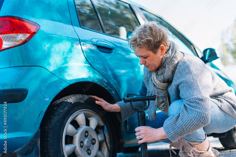 adult woman in the foreground inflating car tyre