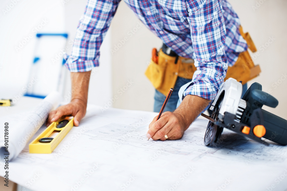 Architect working on blueprint. Closeup of busy architect working on blueprint using level and pencil.