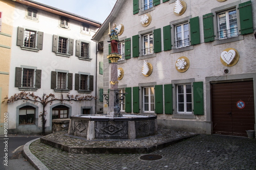 Closeup of a fountain against old-style buildings in Vaud, Switzerland