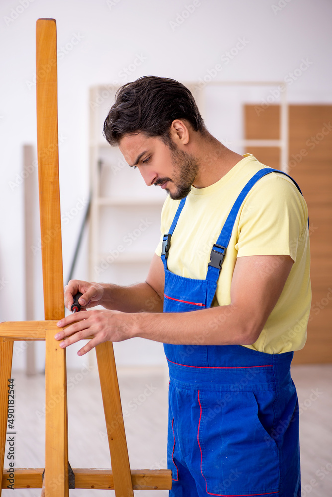 Young male repairman repairing easel at home Young male repairman repairing easel at home