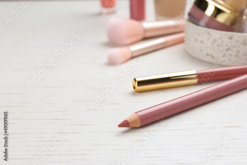 Lip pencils on white wooden table, closeup view with space for text. Cosmetic product