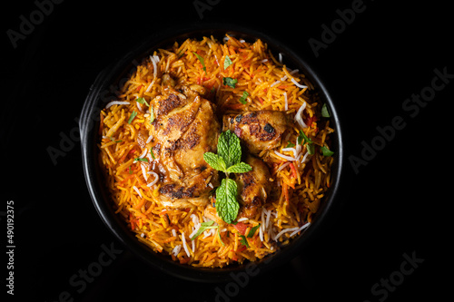 Serving of chicken biryani on a black background © Bite Size01/Wirestock