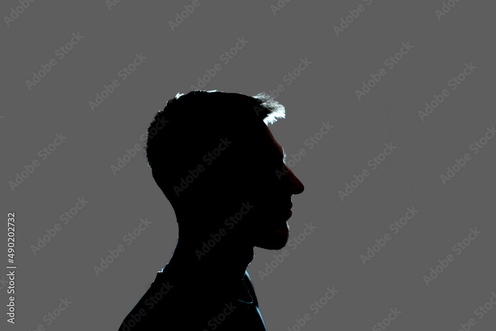 isolated dark male silhouette in the shadow, studio portrait