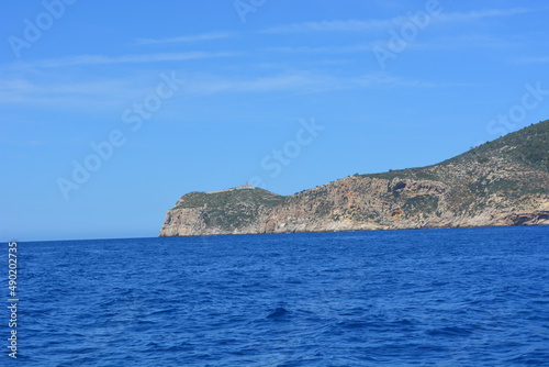 Scenic view of blue ocean waves against mountains on a sunny day in Mallorca, Spain photo