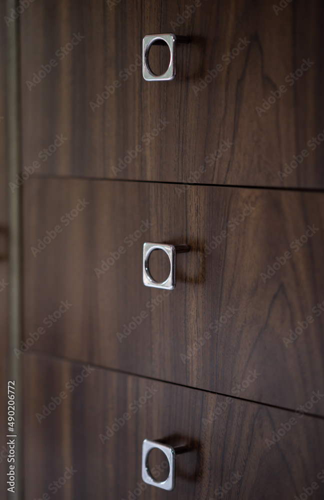 Detalle de manija o asa plateada con estilo de los 70's o viejo para abrir cajón de aglomerado café con vetas Detalle de manija o asa plateada con estilo de los 70's o viejo para abrir cajón de aglomerado café con vetas