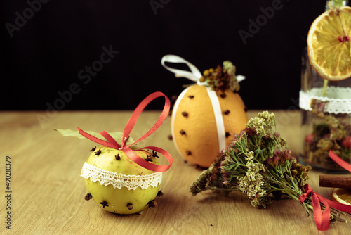 Closeyp of decorated ORANGE AND CLOVES POMANDERS on a wooden table with a black background photo