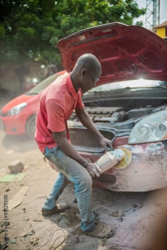 African Auto Bodyworks, Welding a Car in Africa, 2 African men working on a car, African American auto mechanic at work, African American working with electrodes
