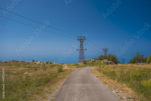 Photography Empty road leading to an island in Croatia surrounded by electrical pylons on a