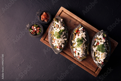 Tlacoyos. Mexican pre hispanic dish made of blue corn flour patty filled with refried beans. Popular street food in Mexico. Flat lay image with copy space.
