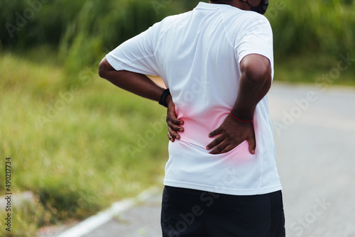 Close up Asian young sport runner black man wear watch feel pain on his spine low back and hip while running at the outdoor street health park, healthy exercise Injury from workout concept © sorapop