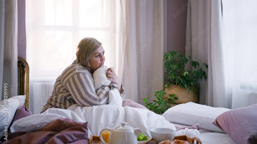 Happy overweight woman having breakfast in bed at home. Happy overweight woman having breakfast in bed at home.