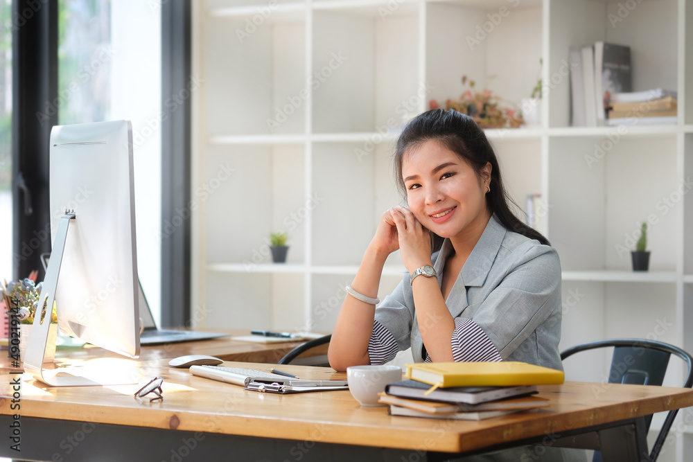 Charming young asian businesswoman sitting at her office desk and smiling to camera. Charming young asian businesswoman sitting at her office desk and smiling to camera.