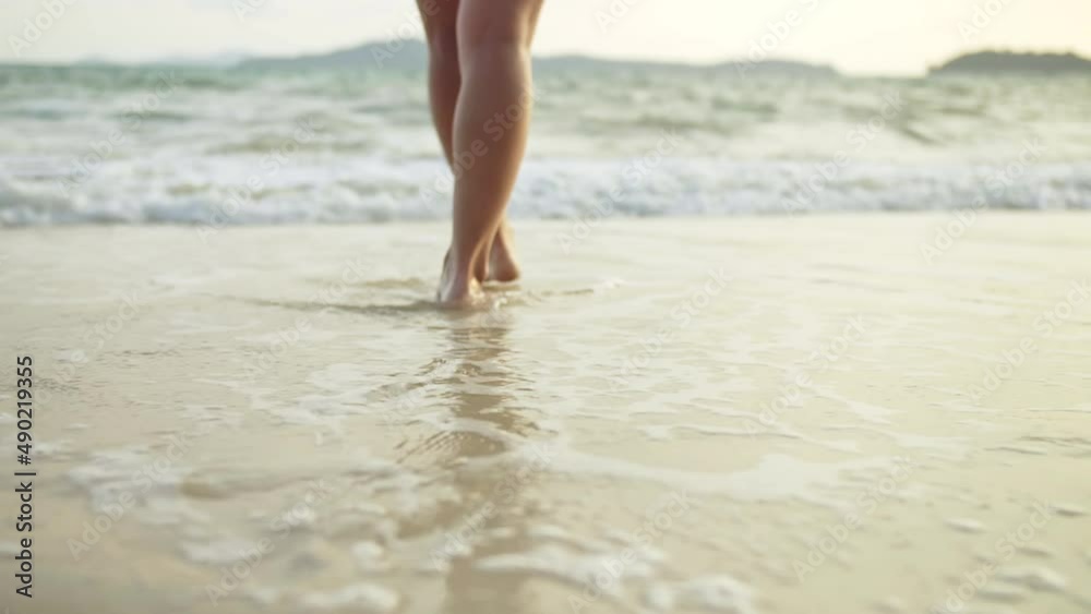 The barefoot woman feet relaxed are lying on the sandy beach and washed by the water and foam of the ocean. Concept relax tropical resort traveling happy summer holiday The barefoot woman feet relaxed are lying on the sandy beach and washed by the water and foam of the ocean. Concept relax tropical resort traveling happy summer holiday