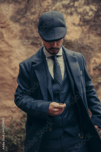 Vertical shot of a Hispanic male in retro 1900s gangster fashion tossing a coin