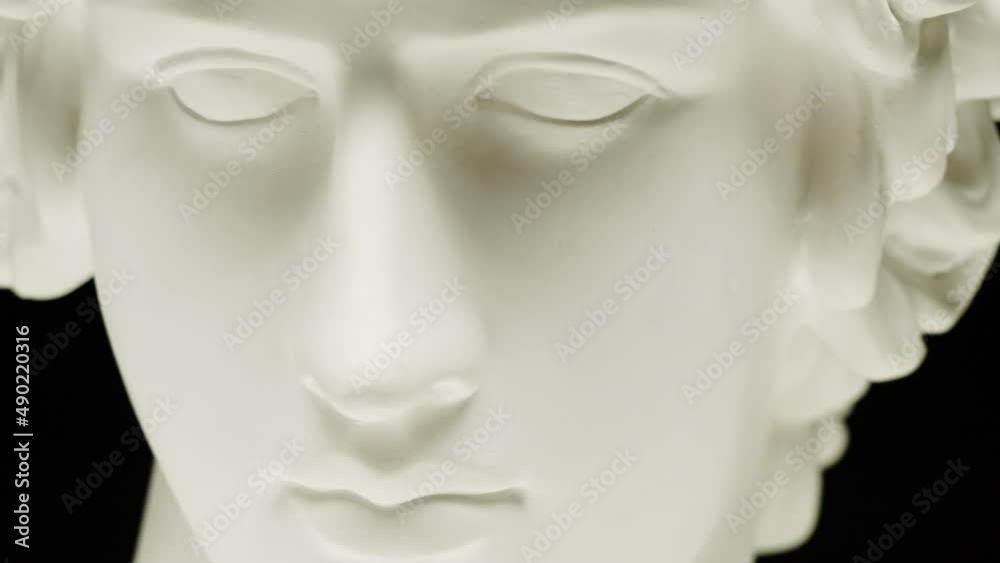 Plaster head sculpture Apollonian close-up. Gypsum ancient statue isolated on black background.