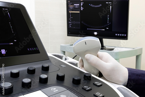 A doctor holding an ultrasound probe by the sonography machine. Professional modern medical investigation concept.
