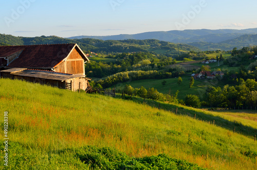 Landscape of a wooden house with greenery on a hilly terrain photo