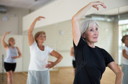 Portrait of a mature woman in a group class, standing on the 4th position of the ballet stand in a dance studio