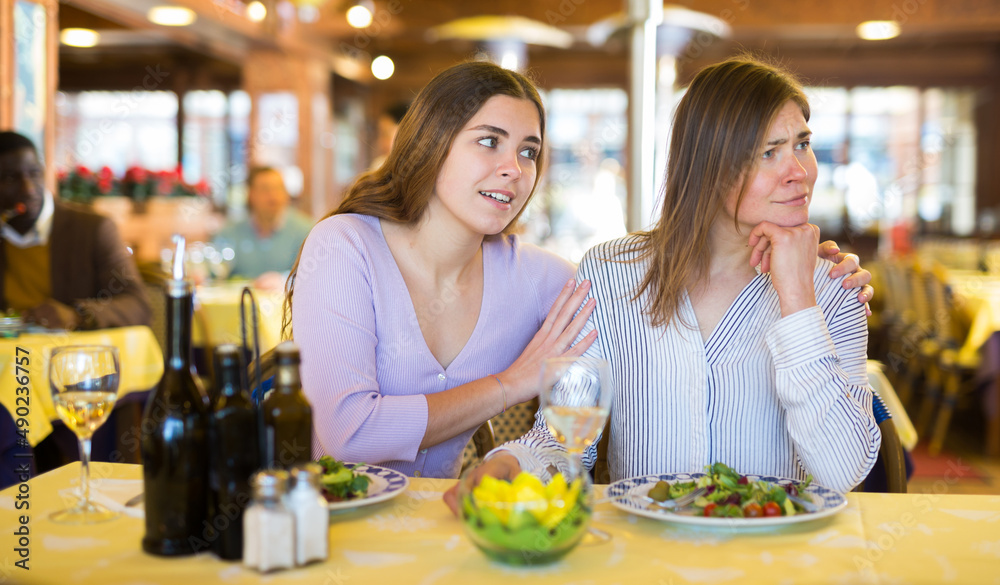 Woman comforting her upset female friend during meeting in restaurant.