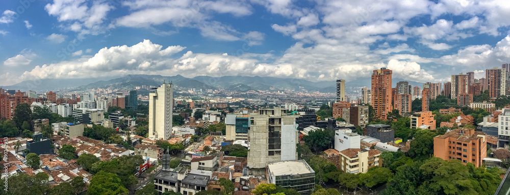 Panoramic view of skyline Medellin with white cloud covered mountains in the back, Colombia