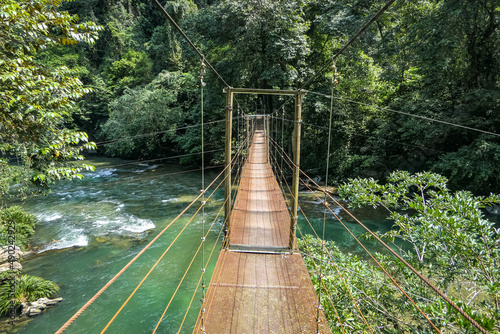 Hanging wooden bridge over Rio Claro Canyon in sunshine, Doradal, Colombia