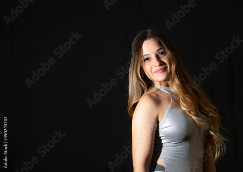 Young latin woman ballet model. with ballet shoes. exercising happy, smiling. with black background and copy space for advertising. low key photo.