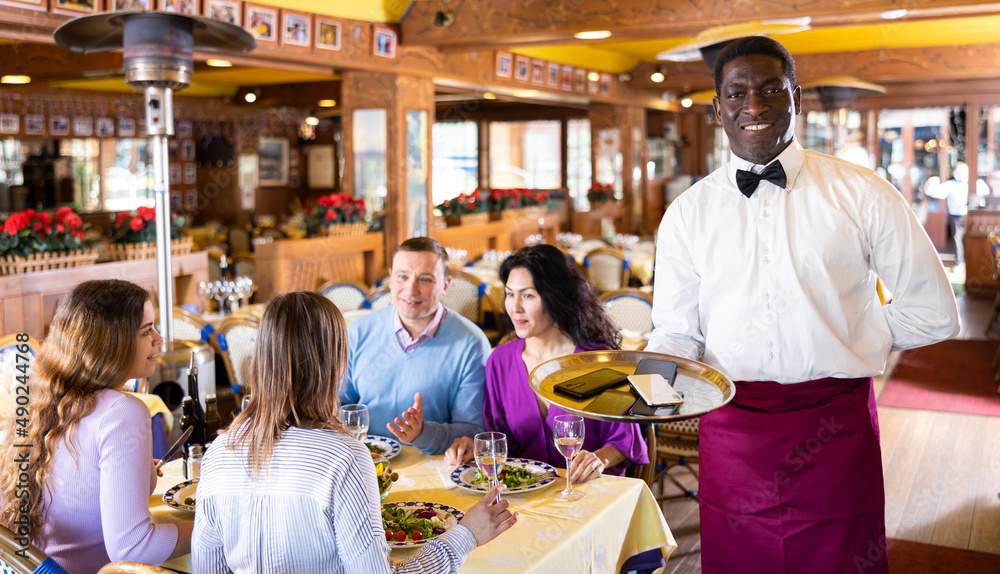 Fototapeta premium African American waiter brought mobile phones on the tray of the restaurant
