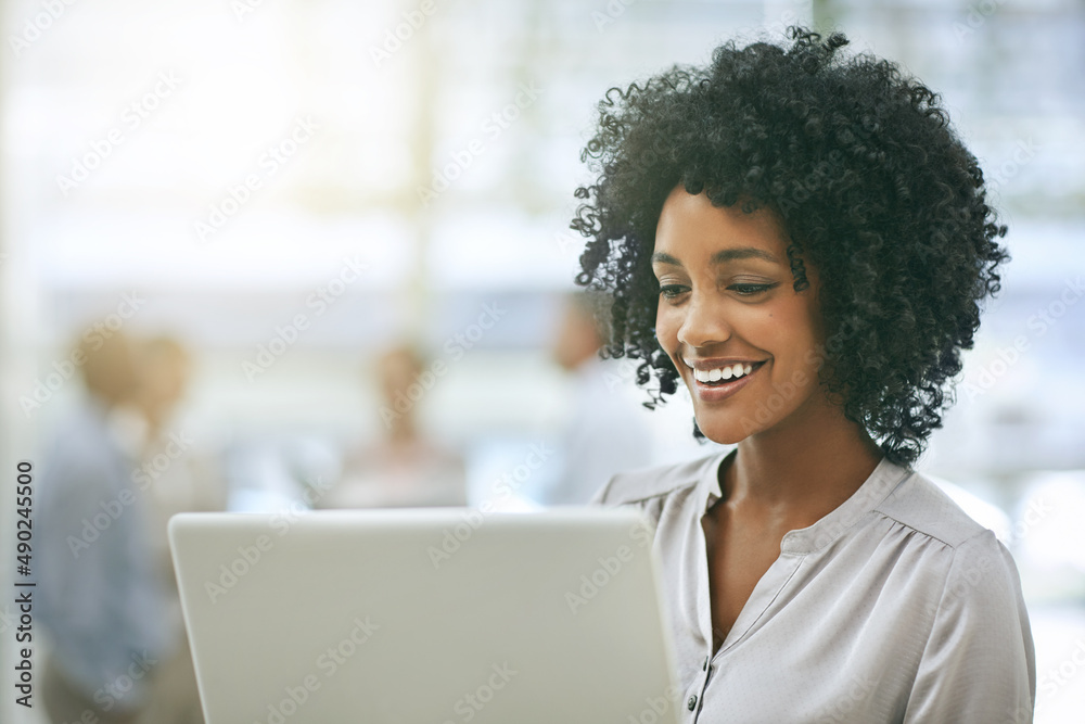 Focused on the task at hand. Cropped shot of a young businesswoman using a laptop with her colleagues in the background. Focused on the task at hand. Cropped shot of a young businesswoman using a laptop with her colleagues in the background.
