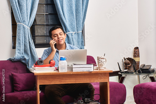 Latin young man doing home office  young man in front of computer in meeting. Video call  talking on the phone. Working from homes. studying remotely.