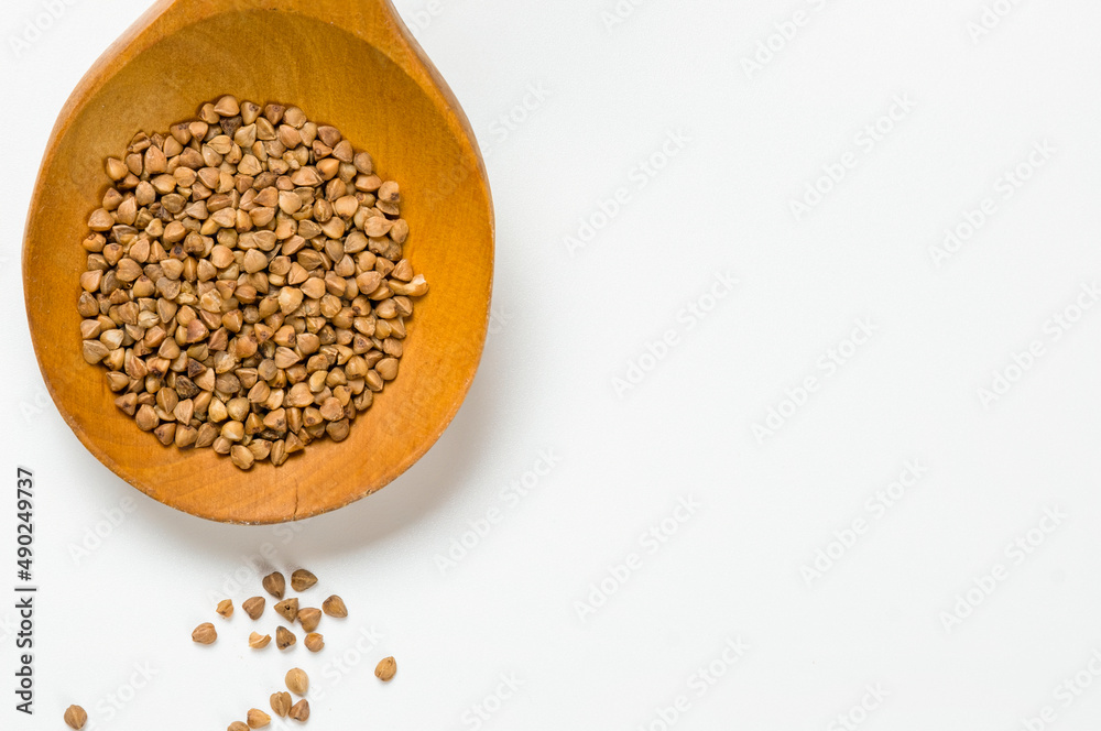 Buckwheat in a wooden spoon on a white background. Buckwheat in a wooden spoon on a white background.