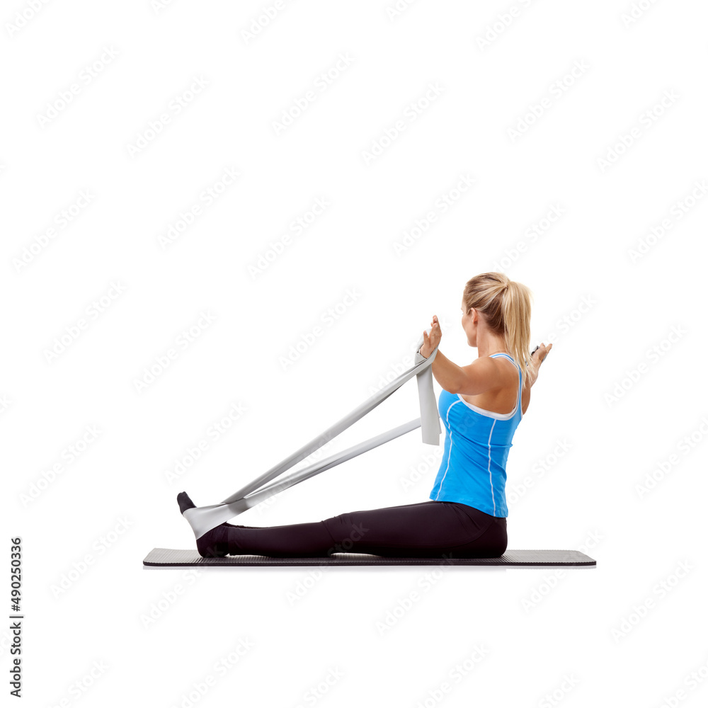 Stretching myself into shape. A young blonde woman sitting on a mat and exercising with a resistance band - rear-view. Stretching myself into shape. A young blonde woman sitting on a mat and exercising with a resistance band - rear-view.